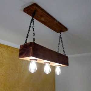 Lustre rústico com bloco de madeira, correntes e três lâmpadas expostas.