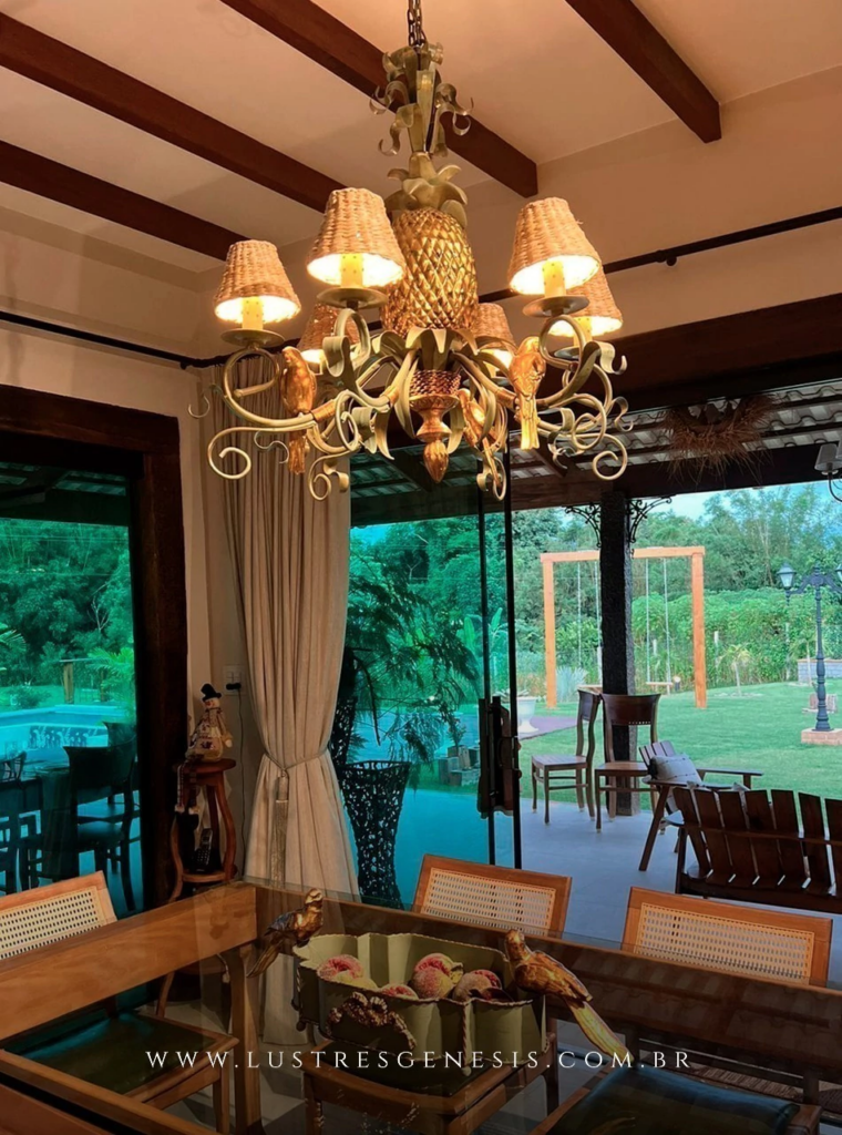 Sala de jantar rústica com lustre rústico e vista para área verde.