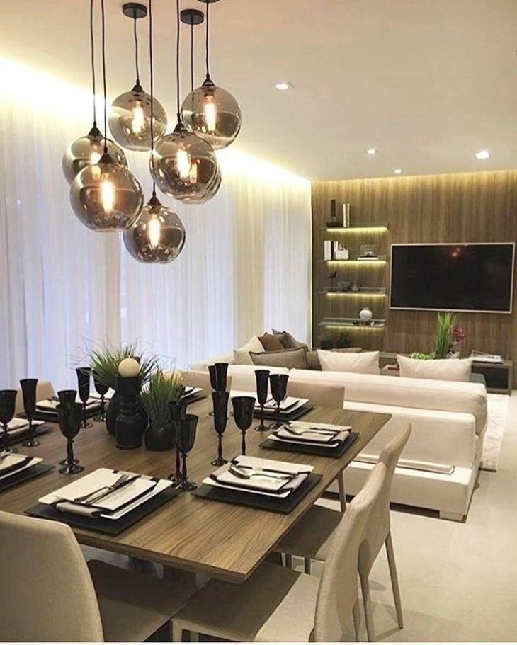 Sala de jantar sofisticada com lustre moderno de globos fumê e mesa elegantemente posta.