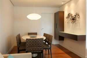 Sala de jantar compacta com mesa redonda e luminária pendente minimalista.