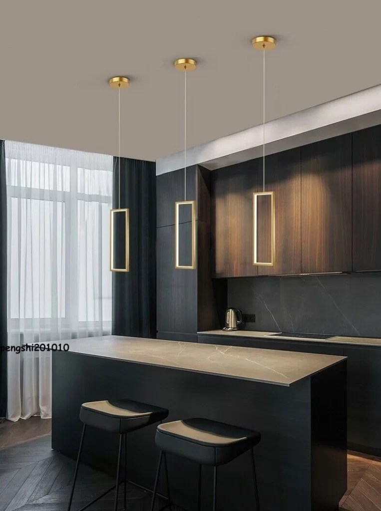 Cozinha sofisticada com pendentes dourados e móveis escuros, com altura ideal pendente.
