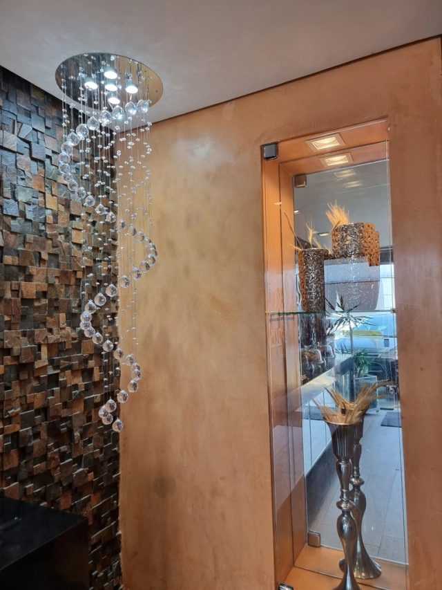 Lustre de cristais suspensos em espiral, com iluminação moderna.