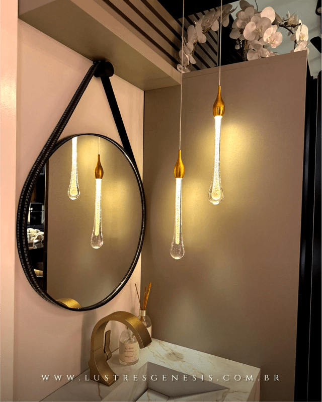 Lustre moderno com pingentes dourados em formato de gotas iluminadas.