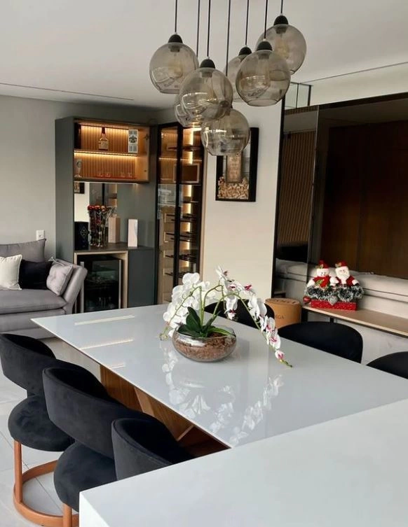 Lustres pendentes com globos em vidro fumê iluminam ambiente integrado.