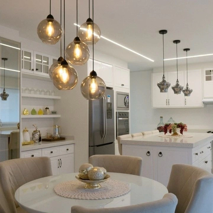 Lustres pendentes com globos em vidro fumê iluminam cozinha sofisticada.