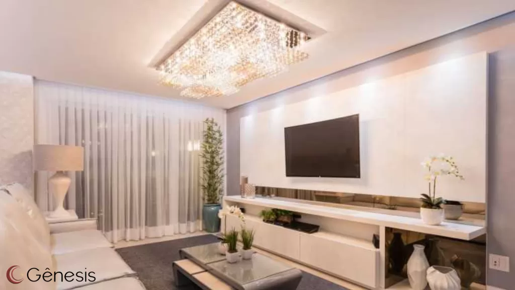 Plafon de cristal retangular embutido no teto, com iluminação brilhante e sofisticada, destacando sala de estar moderna com painel de TV, cortinas claras e decoração elegante em tons neutros.