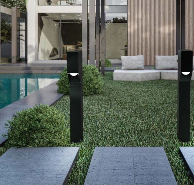 Jardim moderno com iluminação em balizadores pretos ao longo do caminho.