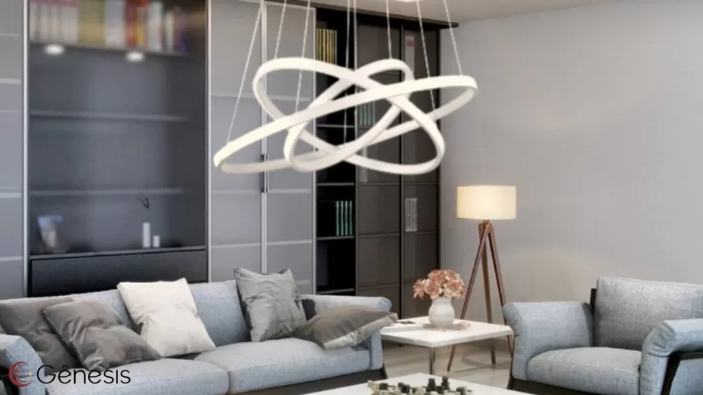 Lustre moderno de LED com design escultural em anéis entrelaçados, instalado em sala de estar contemporânea com sofá cinza, ideal para iluminação decorativa sofisticada e projetos de interiores de alto padrão.