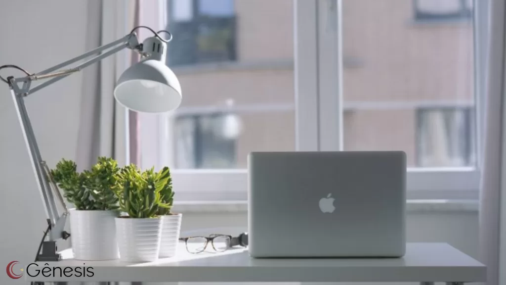 Luminária de mesa branca articulada para escritório home office, ideal para iluminação direcionada em bancada de trabalho, ao lado de notebook e plantas decorativas, proporcionando luz funcional e moderna para estudo e produtividade.