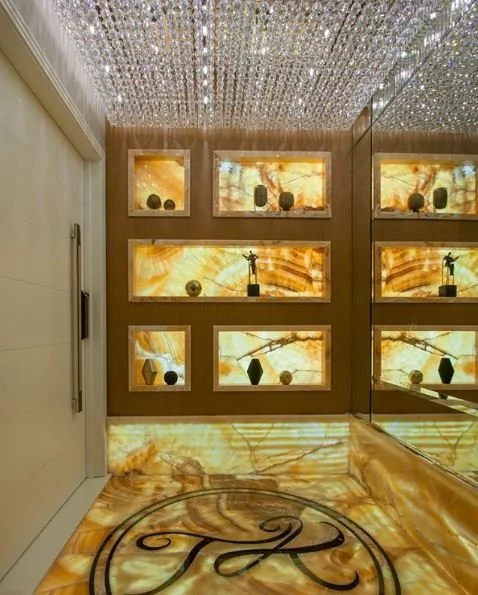 Entrada luxuosa com iluminação em cristal e detalhes em ônix iluminado.