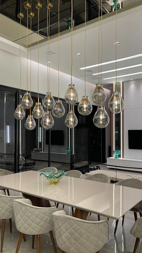 Sala de jantar sofisticada com lustre pendente de vidro e dourado.
