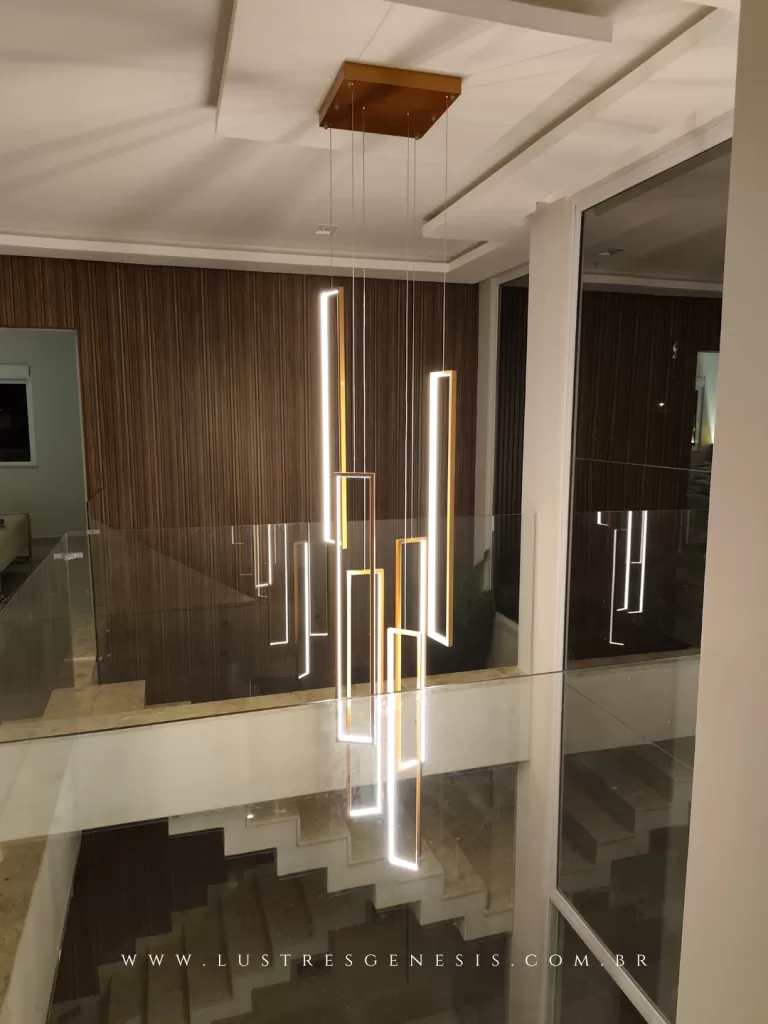 Lustre moderno para pé-direito duplo com barras geométricas em LED, suspenso sobre escada em ambiente contemporâneo, destacando iluminação vertical elegante e design sofisticado.