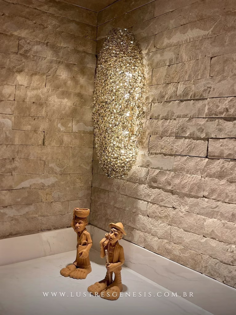 Arandela Dente de Leão de cristal iluminada em parede de pedra, ideal para cabeceira de cama, lavabo e banheiro. Lustres Gênesis loja online de Lustres e Iluminação Decorativa