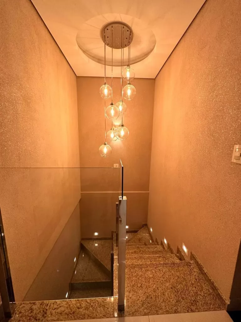 Pendente moderno com múltiplas cúpulas de vidro transparente suspensas em diferentes alturas, ideal para iluminação de escadas e ambientes com pé-direito alto.