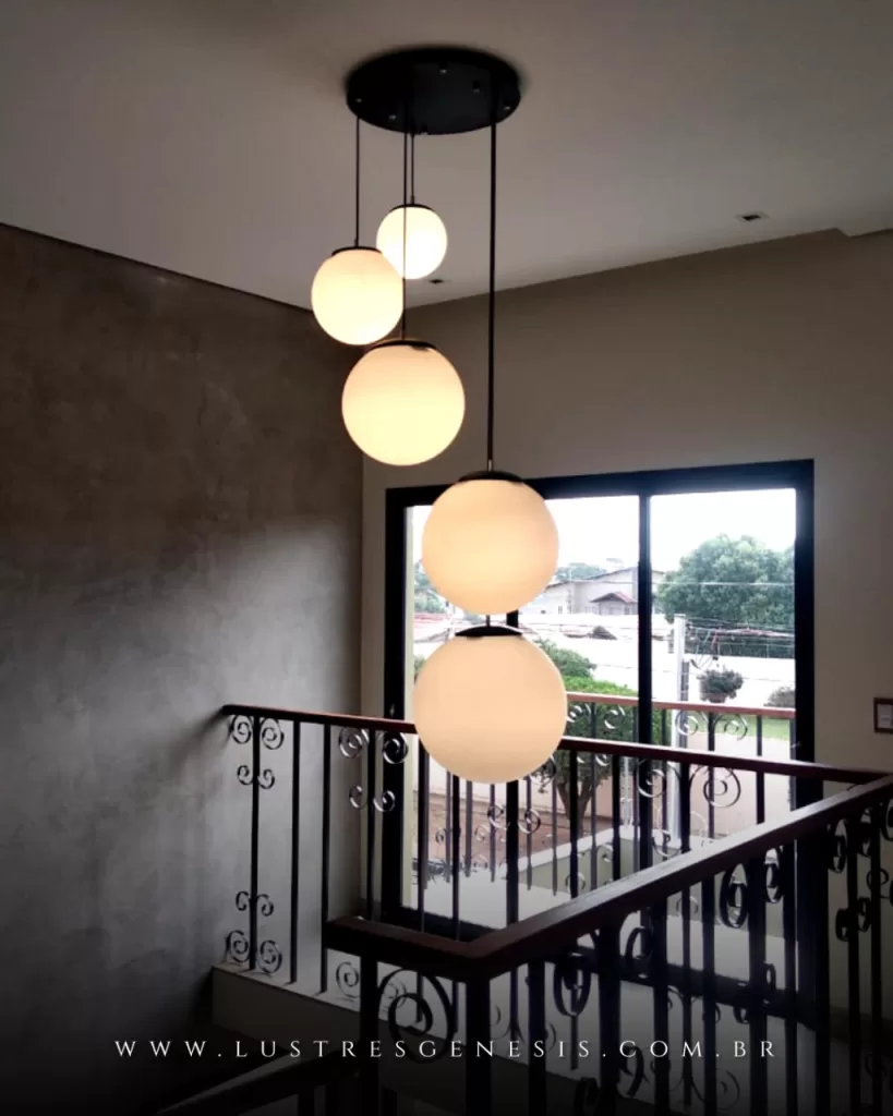 Pendente com globos de vidro leitoso suspensos em diferentes alturas, ideal para escadas e ambientes com pé-direito duplo.