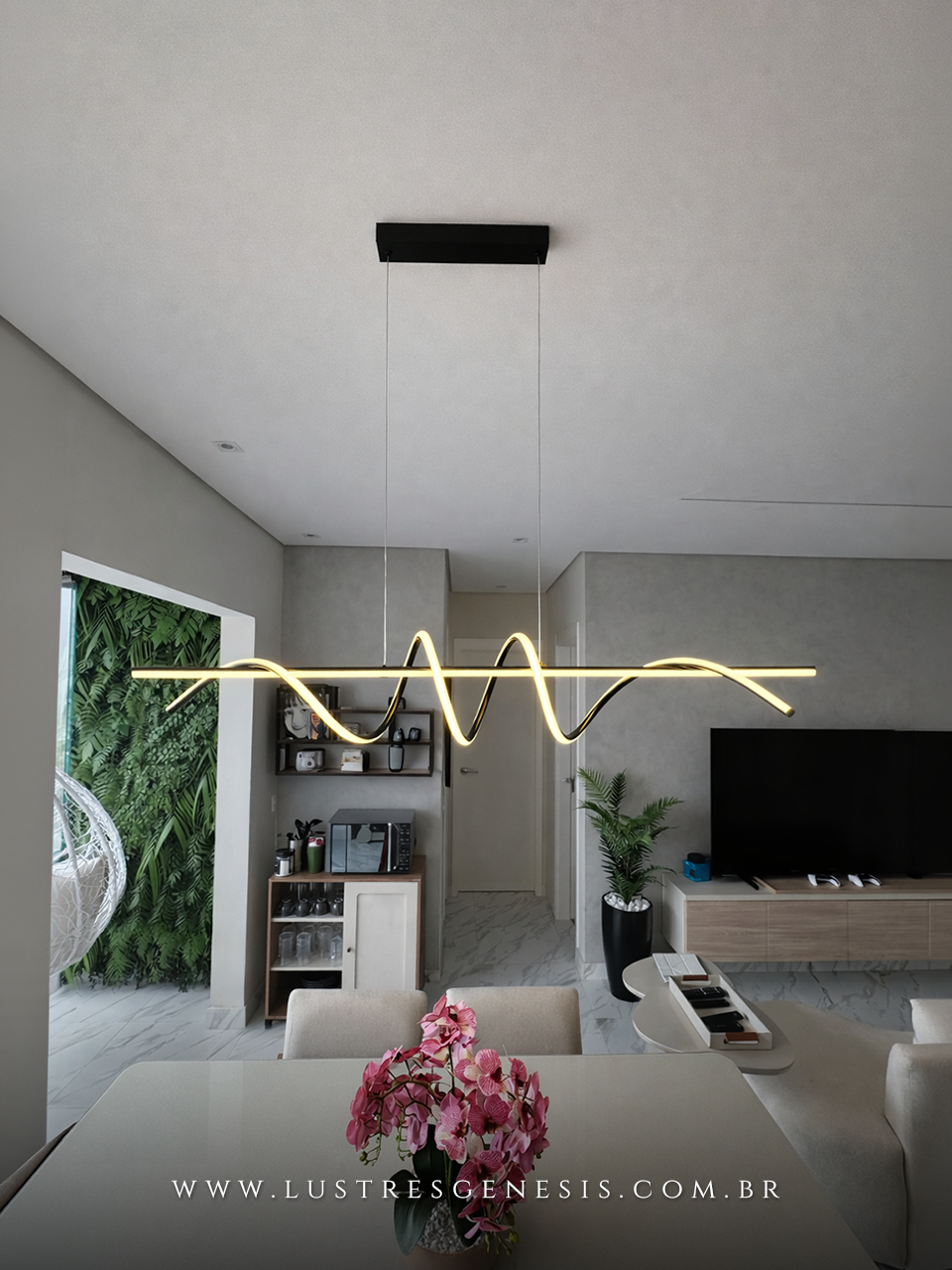Pendente Zeon da Lustres Gênesis instalado na casa da influenciadora Zabetta Macarini, com design moderno em LED linear ondulado, suspenso por cabos finos sobre ambiente contemporâneo, proporcionando iluminação elegante e sofisticada.