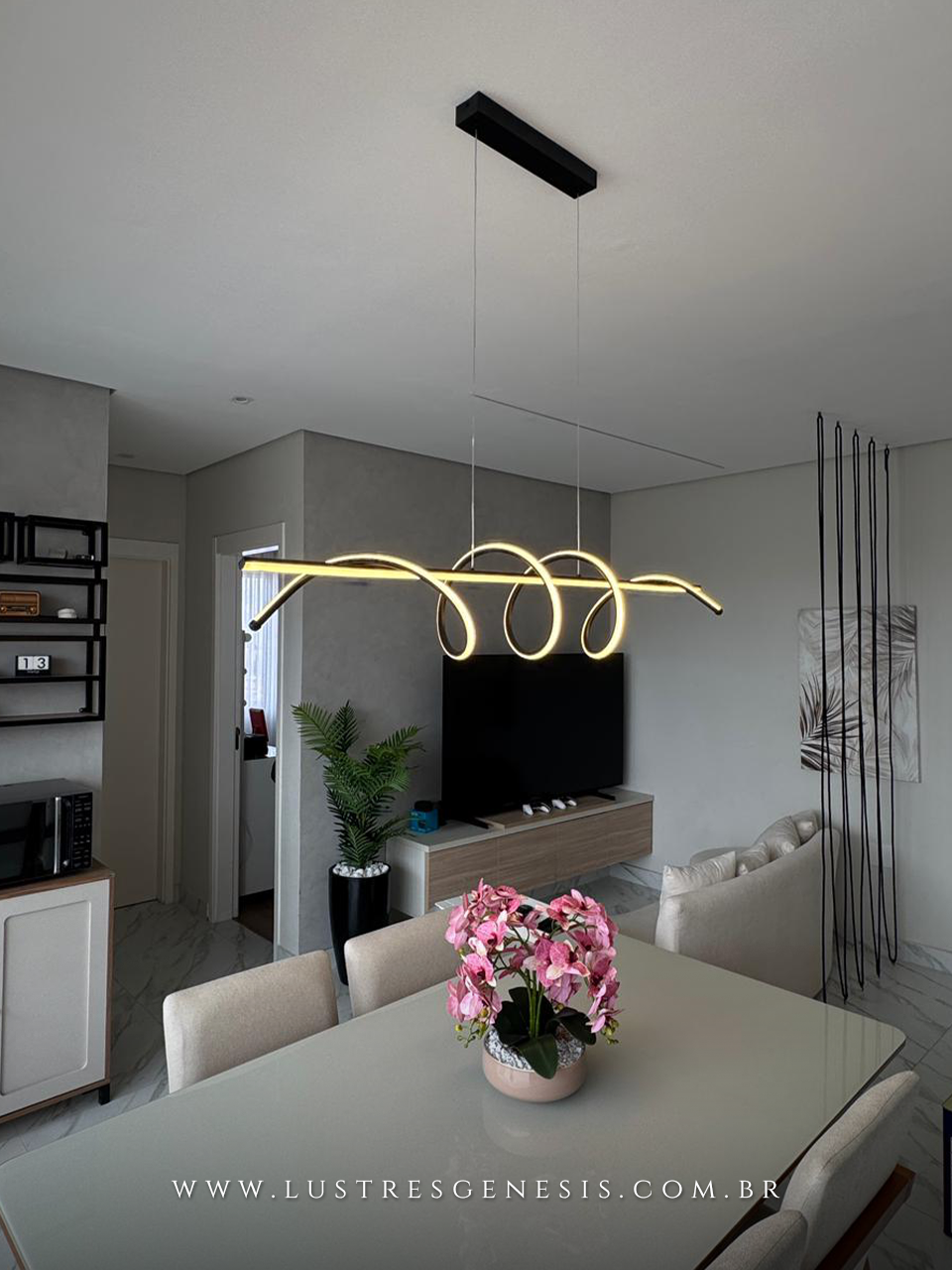 Pendente Zeon da Lustres Gênesis instalado na casa da influenciadora Zabetta Macarini, com design moderno em LED linear ondulado, suspenso por cabos finos sobre ambiente contemporâneo, proporcionando iluminação elegante e sofisticada.