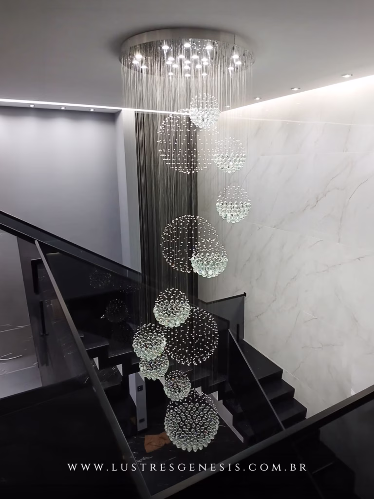 Lustre de Cristal Yôda da Lustres Gênesis instalado em uma escada de pé-direito duplo, com esferas de cristal suspensas em composição cascata para um ambiente sofisticado e contemporâneo.