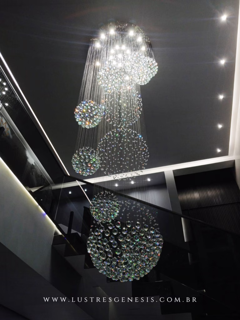 Lustre de Cristal Yôda da Lustres Gênesis instalado em uma escada de pé-direito duplo, com esferas de cristal suspensas em composição cascata para um ambiente sofisticado e contemporâneo.