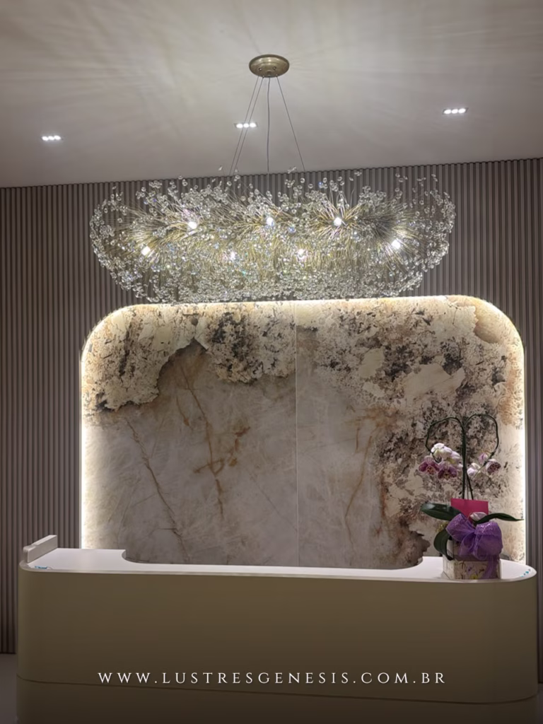 Lustre Retangular Ninho da Lustres Gênesis instalado sobre uma recepção, com estrutura dourada, cristais brilhantes e design sofisticado que valoriza ambientes comerciais de alto padrão.