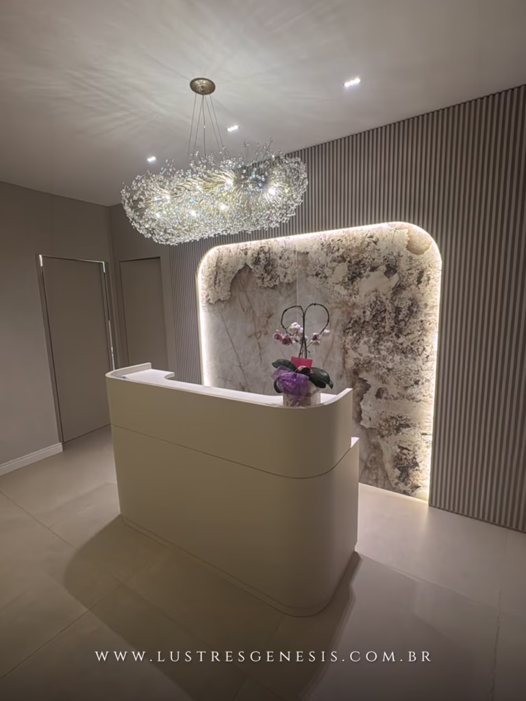 Lustre Retangular Ninho da Lustres Gênesis instalado sobre uma recepção, com estrutura dourada, cristais brilhantes e design sofisticado que valoriza ambientes comerciais de alto padrão.