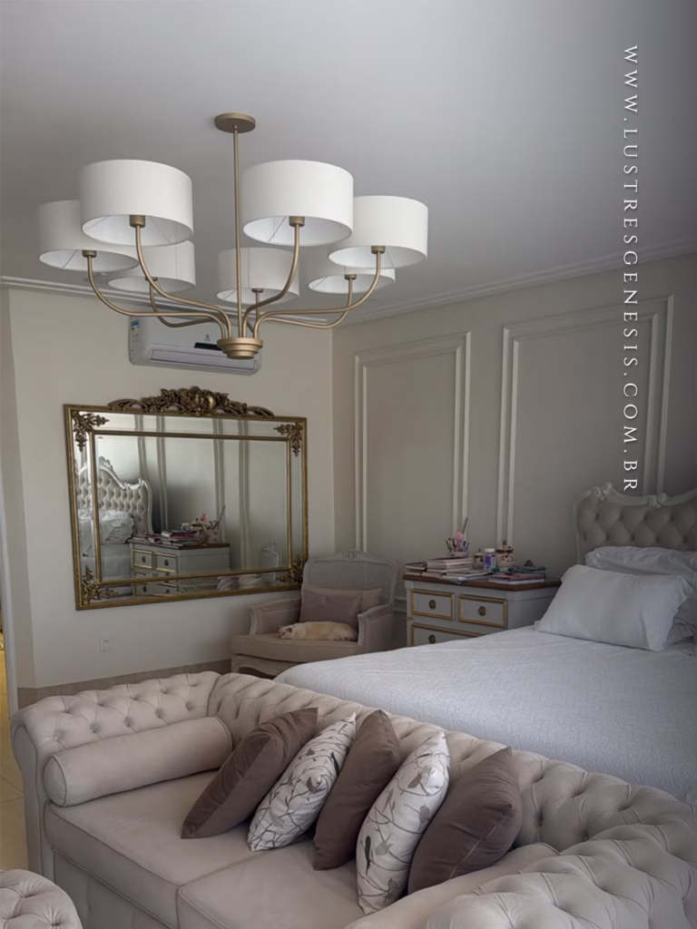Lustre Versos da Lustres Gênesis instalado em quarto elegante, com sete cúpulas brancas e acabamento dourado, proporcionando iluminação sofisticada e aconchegante.