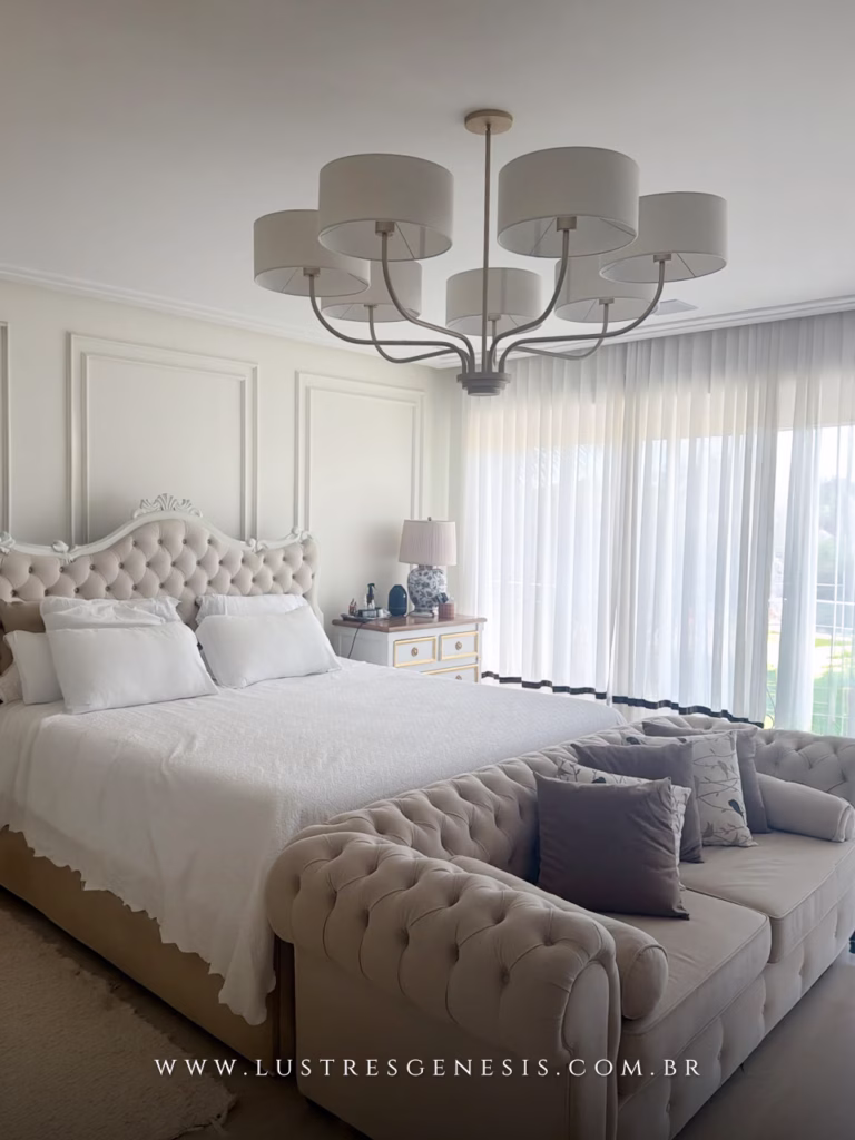 Lustre Versos da Lustres Gênesis instalado em quarto elegante, com sete cúpulas brancas e acabamento dourado, proporcionando iluminação sofisticada e aconchegante.